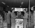 Photograph: [Frank Mills and another man at a grocery store, 3]