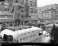 Photograph: [Reporter standing on a automobile]