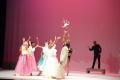 Photograph: [Photograph of a bride throwing a bouquet into the air on stage]