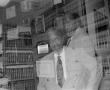 Photograph: [E. Brice Cunningham posing in front of library shelf, 2]