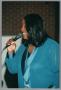 Primary view of [Photograph of a woman singing into a microphone facing towards the left]