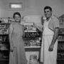Photograph: [Man and woman holding donuts in front of display 2 of 2]