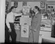 Photograph: [Men standing next to a cigarette display]