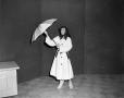 Photograph: [Woman wearing a raincoat and holding an umbrella]