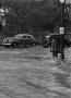Photograph: [A man and automobiles in a flooded street]