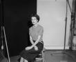 Photograph: [Doris sitting on a stool, in a studio]