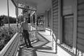 Photograph: [Man leaning against porch railing]