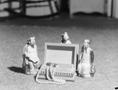 Photograph: [Photograph of three figurines surrounding a small chest]
