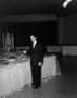 Photograph: [Man in formal attire standing next to a table of food]
