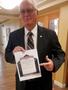 Photograph: [Gary Lovell holds event flyer at TXSSAR Dallas Chapter meeting]