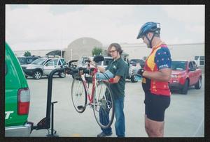 Primary view of object titled '[Volunteer unloading a cyclists bike from a bike rack: Lone Star Ride 2004 event photo]'.