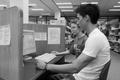 Photograph: [Library employee helps student on computer, 1]