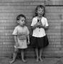 Photograph: [Two children standing in front of a brick wall #9]