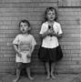 Photograph: [Two children standing in front of a brick wall #10]
