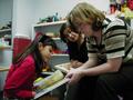 Photograph: [Young girl reads to ILD tutors]