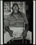 Photograph: [Man seated in a chair, holding a cane and a soda can]