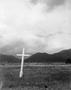Photograph: [White cross silhouetted by dark mountains]