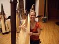 Photograph: [Dr. Jaymee Haefner sitting behind a harp onstage]