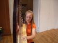 Photograph: [A girl in an orange shirt sitting behind a harp]