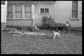 Photograph: [Child and dog in a backyard with a water hose]