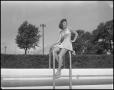 Photograph: [Woman sits on pool railing]