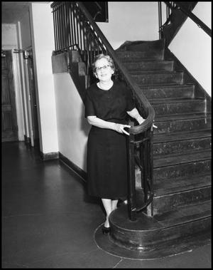 Primary view of object titled '[Woman stands at the bottom of the stairs]'.