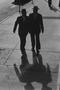 Photograph: [Two silhouetted men on a sidewalk]