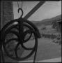 Photograph: [Pulley wheel hanging outside, 4]