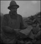 Photograph: [Photograph of a man inspecting a rock]