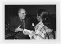 Photograph: [Unidentified man wearing glasses speaks to a student]