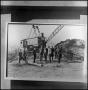 Photograph: [Print of men standing in front of crane]