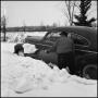 Photograph: [Man shoveling snow away from his car]