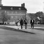 Photograph: [Four people walking in front of the Hurley Administration Building]