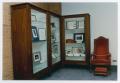 Photograph: [Display cabinet and chair]