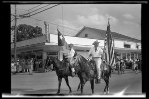 Primary view of object titled '[Woman on Horseback with Texas Flag & Man on Horseback with American Flag]'.