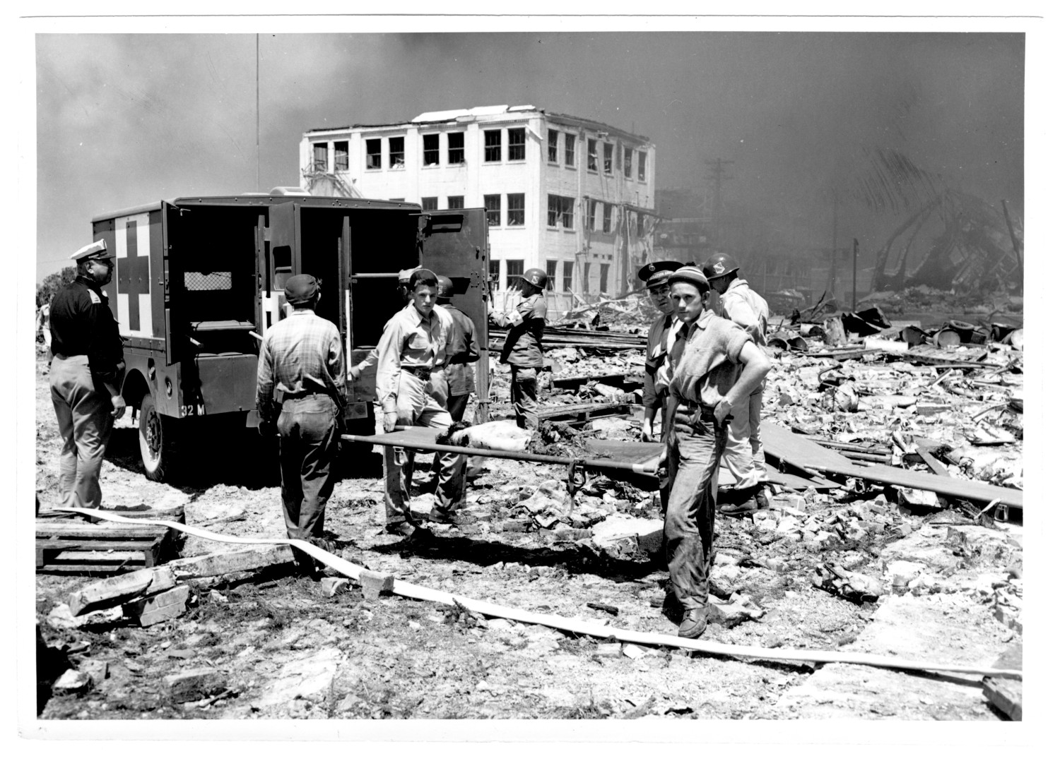 [Rescue workers holding a stretcher near an ambulance after the 1947 Texas City ...
