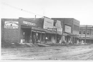 Primary view of object titled '[Street scene in Rosenberg, City Drug Store to the left]'.