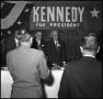 Photograph: [Gentlemen Smile Under Kennedy Banner]