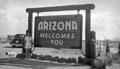 Photograph: [Woman Poses with "Arizona Welcomes You" Sign]