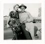 Text: [Photo of Ed Hildebrand sitting on an automobile with unknown woman]