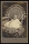 Photograph: [Portrait of a Baby in a Cushioned Wicker Chair]