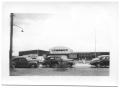Photograph: [Cars Parked in Front of Labor Camp Auditorium]
