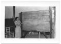 Photograph: [Teacher Pointing to a Lesson on a Chalkboard]