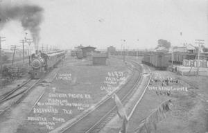 Primary view of object titled '[Railroad Yard in Rosenberg, train approaching to the left]'.