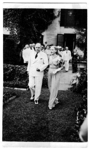 Primary view of object titled '[Mary Van den Berge Hill walking with unidentified man in white suit]'.