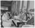 Photograph: [Men and women gathered around dining table at Villa Capri]