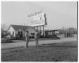 Photograph: [Two men standing across the road from a Butter Krust billboard]