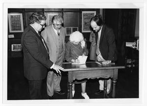 Primary view of object titled '[Irene Salce de Urbina signing a book with Tom Kreneck and others]'.