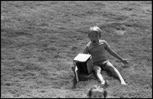 Primary view of object titled '[Child Sliding Down Hill at the Texas Folklife Festival]'.