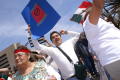 Photograph: [Protesters hold up signs and a Mexican flag]